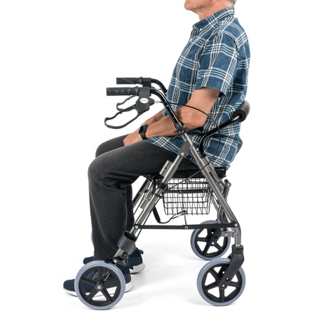 Side view of aluminium rollator showing a person sitting on the reversible seat with compact frame and footrest.