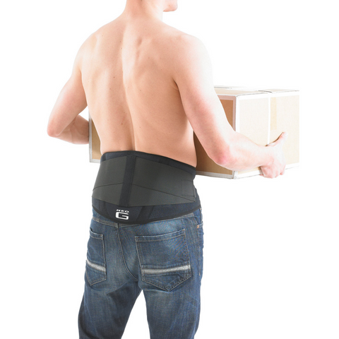 Person wearing the Neo G back brace while standing in a work environment, demonstrating support during occupational activity.