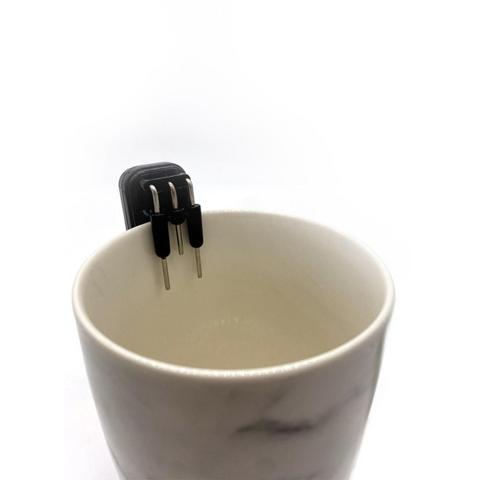 Image of the level liquid indicator inserted into a cup to ensure filling level and no spilling of liquid. First prongs are warning level that beep when the liquid passes them, second beep is the last level of prongs to let the user know that the item is filled.