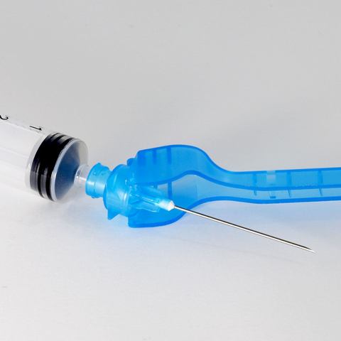  Close-up of the hypodermic safety needle showing the integrated safety device. The safety cap features needle hooking teeth for secure attachment.