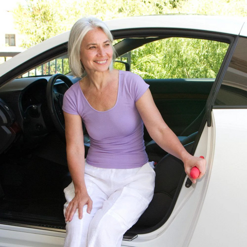 A person using the HandyBar for balance while getting out of a car, demonstrating its ergonomic support.