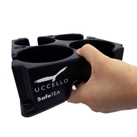 A person holding the Muggi Cup Holder with one hand using the thumb grips, demonstrating the ease of one-handed carrying for users with limited mobility.