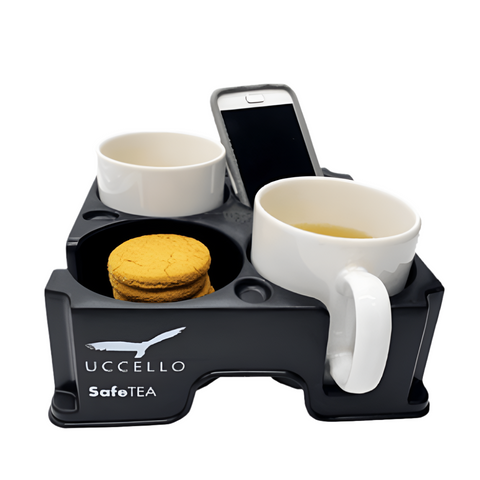 The uccello Muggi cup holder safe tea carrying a phone, two cups, and a plate of biscuits, showcasing its versatility for transporting various items beyond drinks.