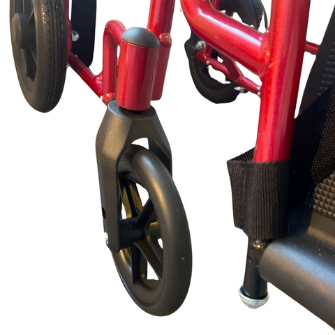 A folded i-Lite Travel Transit Wheelchair being carried by a caregiver, showing its lightweight build.